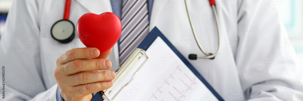 Male medicine doctor hands holding red toy heart - obrazy, fototapety, plakaty 