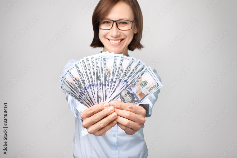Beautiful woman with dollars in hands on gray background Beautiful woman with dollars in hands on gray background
