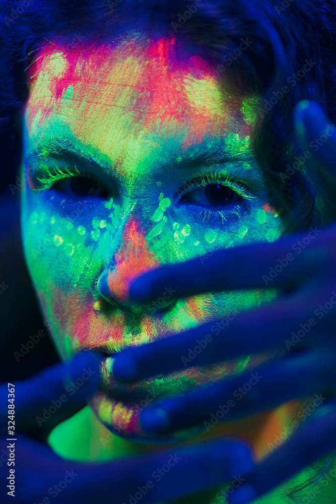 Woman with fluorescent make-up and hand on her face