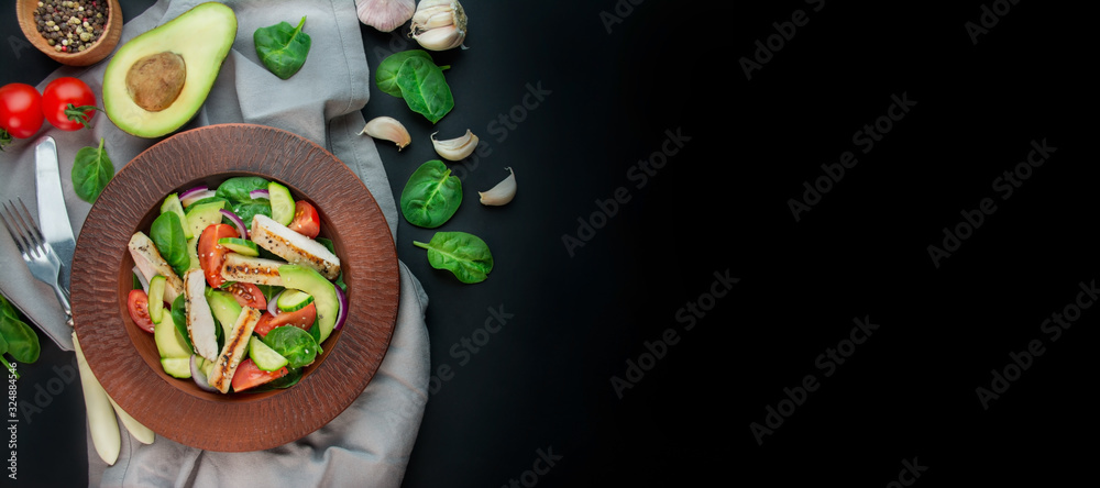 A healthy salad of chicken breast, fresh vegetables, spinach leaves, avocado and tomatoes on a dark background. Salad of greens with meat. The concept of diet food. Copy space. Benner food.