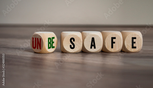 Cubes and dice with unsafe and be safe on wooden background