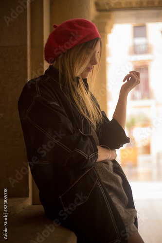 Street style, a young caucasian blonde with a Parisian look and a red hat