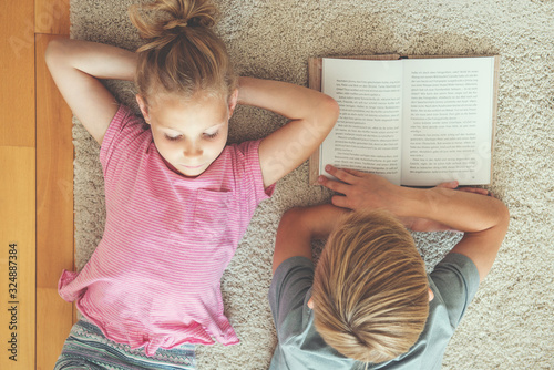 Two cute cildren reading books lying on the floor photo