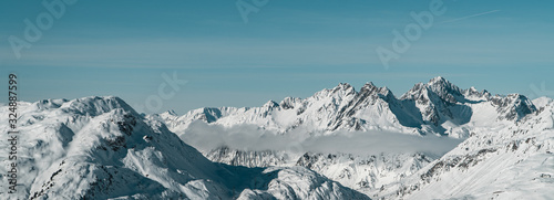 Magical Austrian Alps panorama view - horizontal image of mountains with clouds, snowy peaks and pine trees near St. Anton