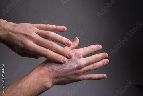 skin care, hands smeared with cream on dark background.