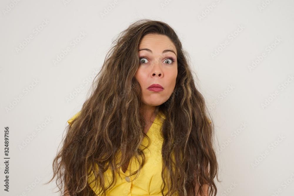Beautiful woman with snobbish expression curving lips and raising eyebrows, looking with doubtful and skeptical expression, suspect and doubt. Standing indoors over gray background. Beautiful woman with snobbish expression curving lips and raising eyebrows, looking with doubtful and skeptical expression, suspect and doubt. Standing indoors over gray background.