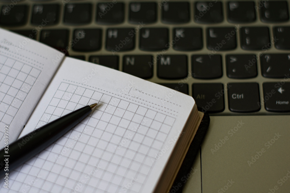 notebook with open sheets and a pen lying on a laptop notebook with open sheets and a pen lying on a laptop