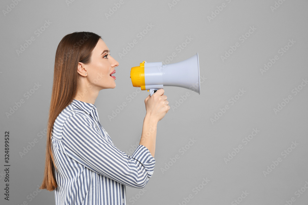 Young woman with megaphone on light grey background Young woman with megaphone on light grey background