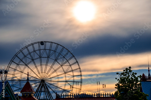 Silhouette of ferris wheel with alone cabin on the blue and orange cloudy sky backgorund against the sunset. Mood concept.
