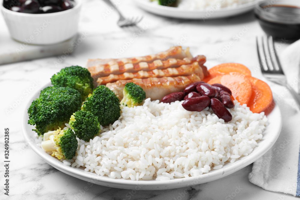Delicious rice with beans and meat served on white marble table, closeup