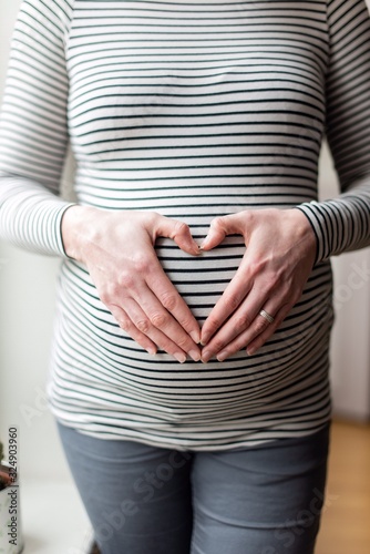 Canvas Print pregnant woman with hands shaping heart on her belly