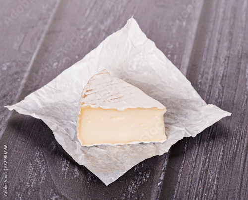 brie cheese in white paper on a wooden table