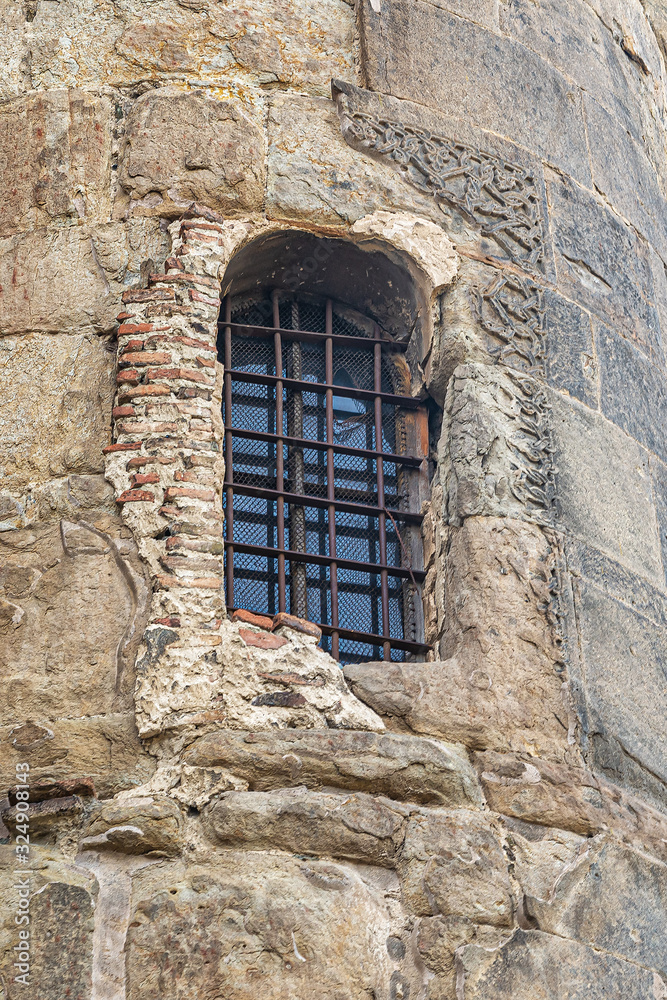 Church window is reinforced with bars and bricks in the stone wall