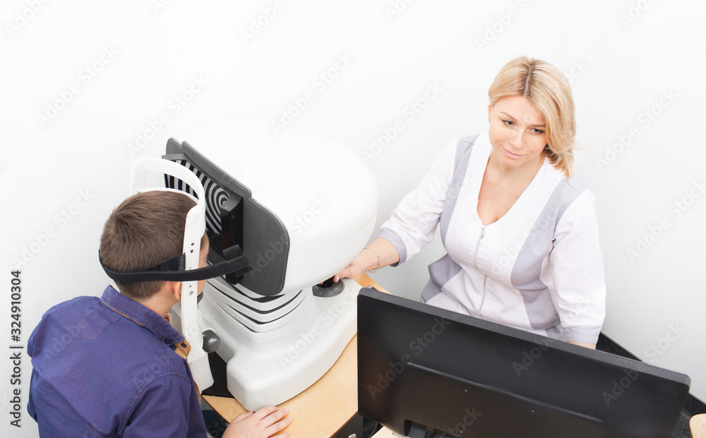 Female optometrist examines a boy’s cornea using a special ophthalmic apparatus. Glaucoma treatment