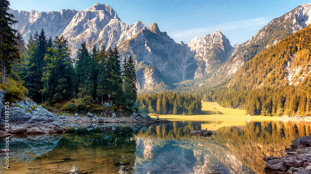Wonderful Autumn landscape during sunset. Great view on fairy tale Fusine lake under sunlight.  Picturesque view of nature. Amazing natural Background. Best popular places for travew. Beauty of World