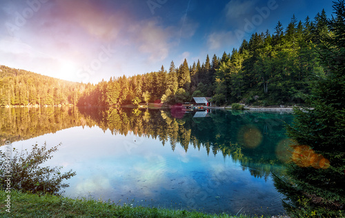 Scenic image of fairy-tale Mountains lake in sunlit. Amazing Nature Landscape. Wonderful Autumn morning. Beautiful scenery of the majestic Fusine lakeside in Julian Alps. Perfect natural background