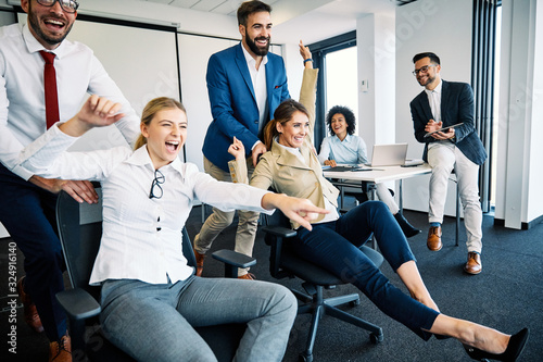 young business people office taking abreak humor pushing chairs