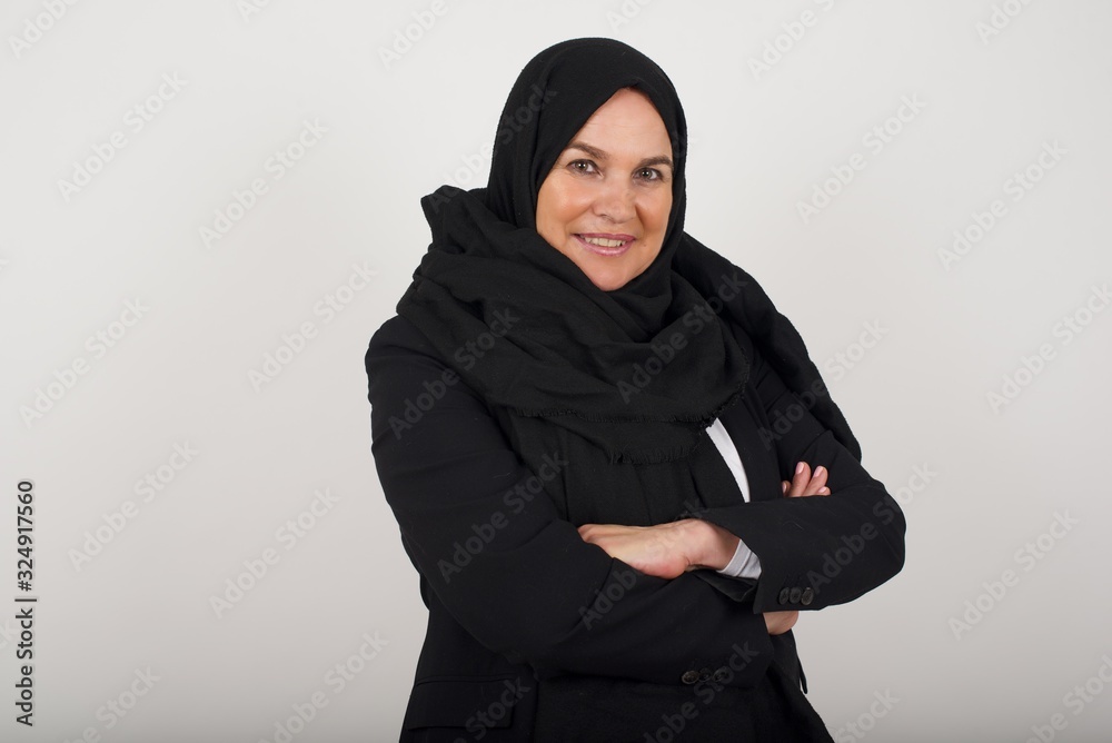 Pretty caucasian lady standing against gray wall with arms crossed wearing casual clothes. Looking and smiling at the camera. Confident successful woman. Pretty caucasian lady standing against gray wall with arms crossed wearing casual clothes. Looking and smiling at the camera. Confident successful woman.