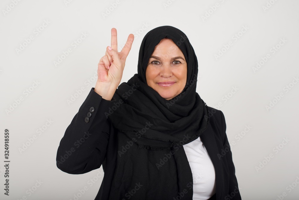 Young caucasian woman standing against gray wall showing and pointing up with fingers number two while smiling confident and happy. Young caucasian woman standing against gray wall showing and pointing up with fingers number two while smiling confident and happy.