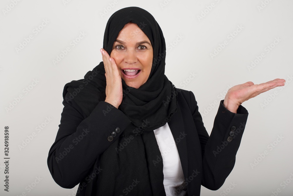 Positive glad female says: wow how exciting it is, has amazed expression, indicates something. Joyful pretty young woman demonstrates something. One hand on her head and pointing with other hand. Positive glad female says: wow how exciting it is, has amazed expression, indicates something. Joyful pretty young woman demonstrates something. One hand on her head and pointing with other hand.