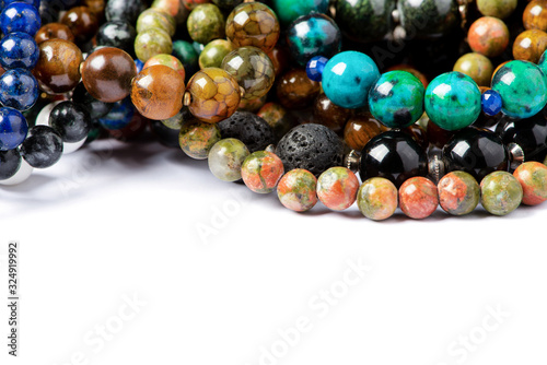 Fototapeta Different natural stone beads on a white background, close-up, free space for text