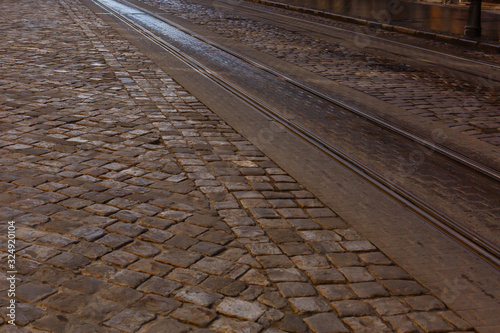 City street at night, tram rails beside a cobblestone road. Black background