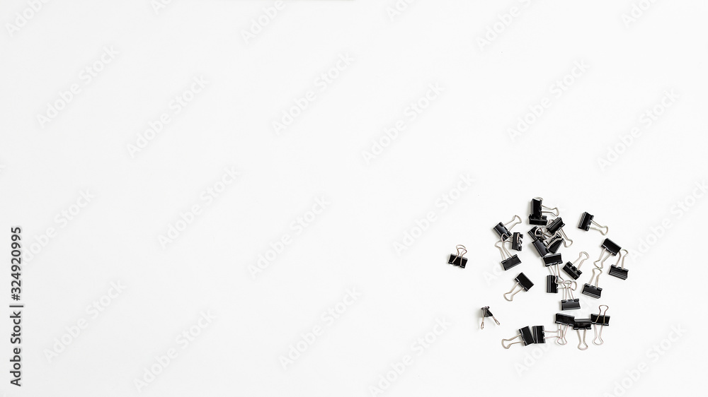 bunch of black binder clips for documents scattered in heap on white background. many stationery clips isolated flat lay. top view of office equipment with copyspace. Place for text