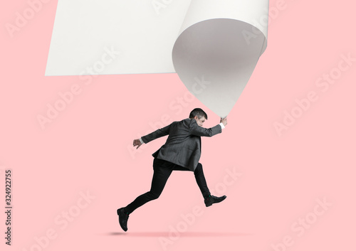 Imagine who's covering white sheet to get digital file icon. Office style young man catching the edge of huge paper sheet. Digital world, funny imagination of the way the icon's appearing.