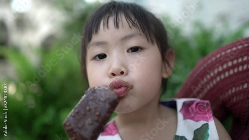 Little asian girl eating ice cream, She smiling and looking at camera. Kid eat ice cream happily. Happy family concept. Handheld shot and Real life.