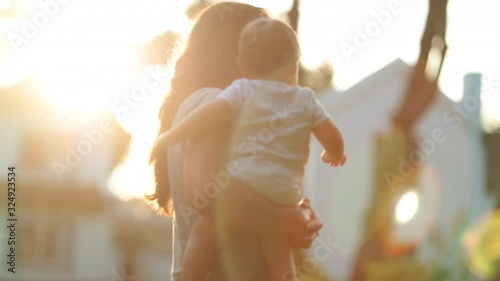 Mother holding baby infant outside during summer sunnset time photo