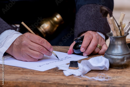 Close-up of a medieval scribe, with a pen, paper and an inkwell