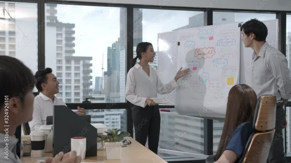 Young asian business woman presenting data idea marketing on board in office. Asia woman show mind mapping and ideas to business partner or colleagues group enjoy teamwork in small office