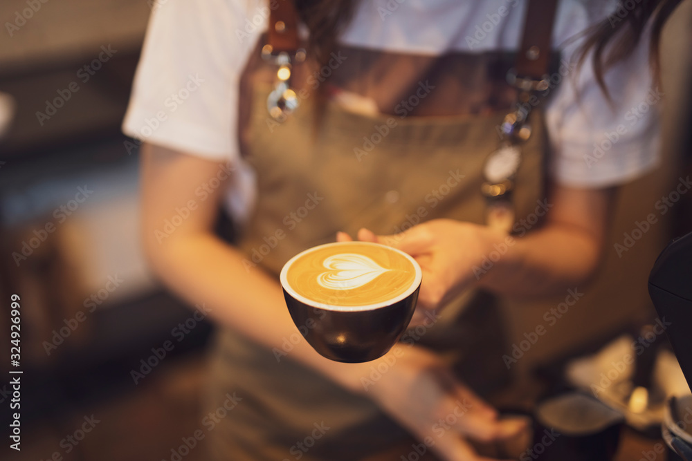 Closeup cup of coffee with pouring milk in a female barista hands Closeup cup of coffee with pouring milk in a female barista hands