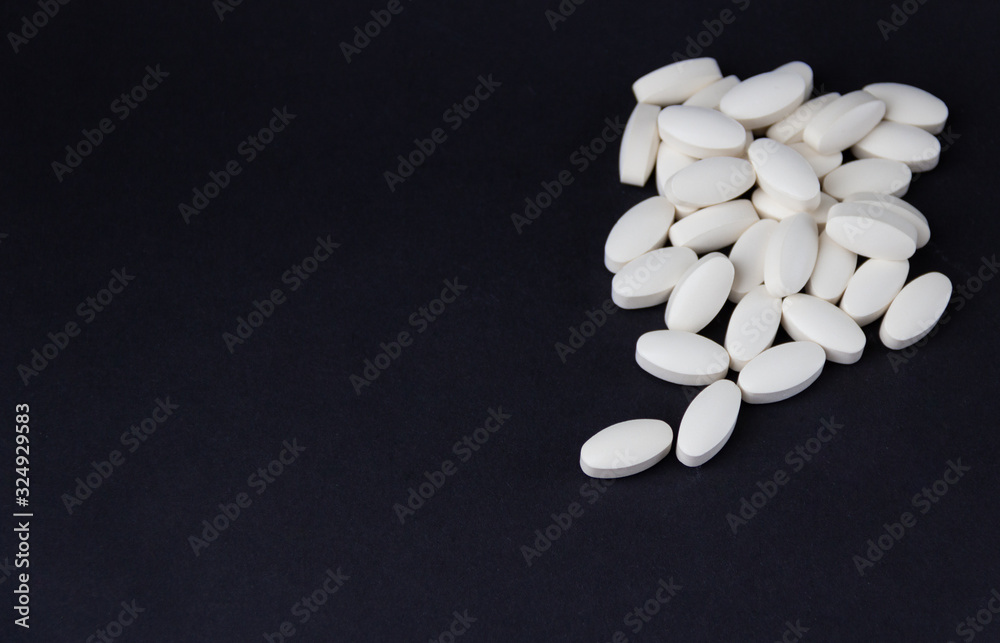 White pills on black background. Free copy space. Medical concept. White pills on black background. Free copy space. Medical concept.