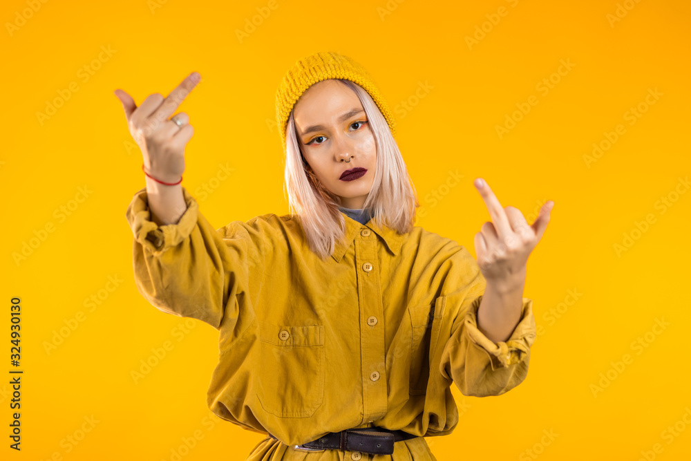 Young rude woman on yellow background showing middle finger - gesture of fuck.