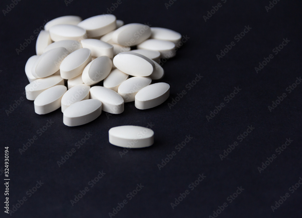 White pills on black background. Free copy space. Medical concept.