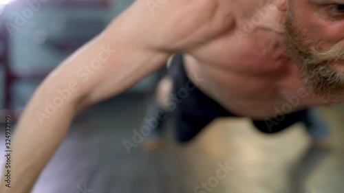 Man Perseveres While Doing Side by Side Pushups in an Indoor Gym photo