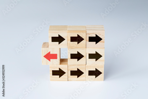 Photos Wooden blocks with several black arrows and one block with red arrow facing the opposite direction