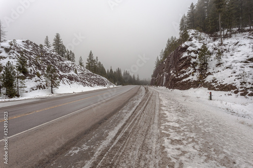 Fog, snow and ice surround an empty highway pass on gloomy day © Richard