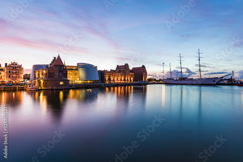 Germany, Mecklenburg-Western Pomerania, Stralsund, Waterfront of coastal town at dusk with sailing ship and Ozeaneum in background photo