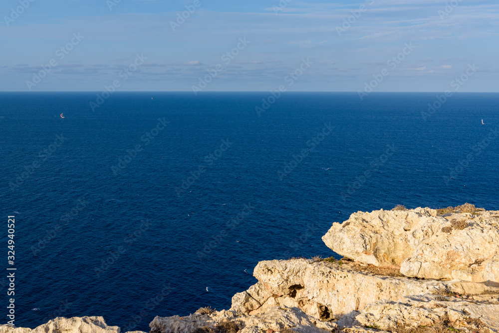 Rocks and blue sea at the northernmost point of Menorca island. Cape of Cavalleria. Baleares, Spain Rocks and blue sea at the northernmost point of Menorca island. Cape of Cavalleria. Baleares, Spain
