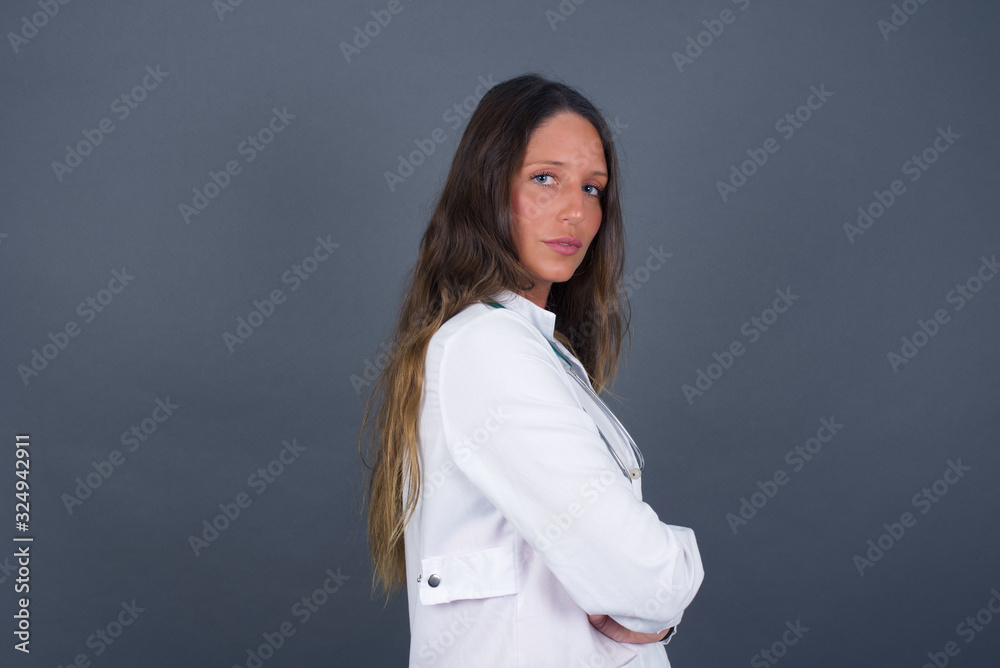 Profile of doctor woman with healthy pure skin has braided hairstyle wears black clothes has contemplative expression ready to have outdoor walk isolated over grey studio wall with copy space. Profile of doctor woman with healthy pure skin has braided hairstyle wears black clothes has contemplative expression ready to have outdoor walk isolated over grey studio wall with copy space.