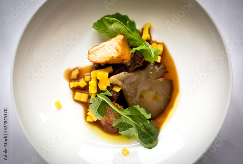 Beef tongue with mushrooms, mango and arugula served in bowl photo