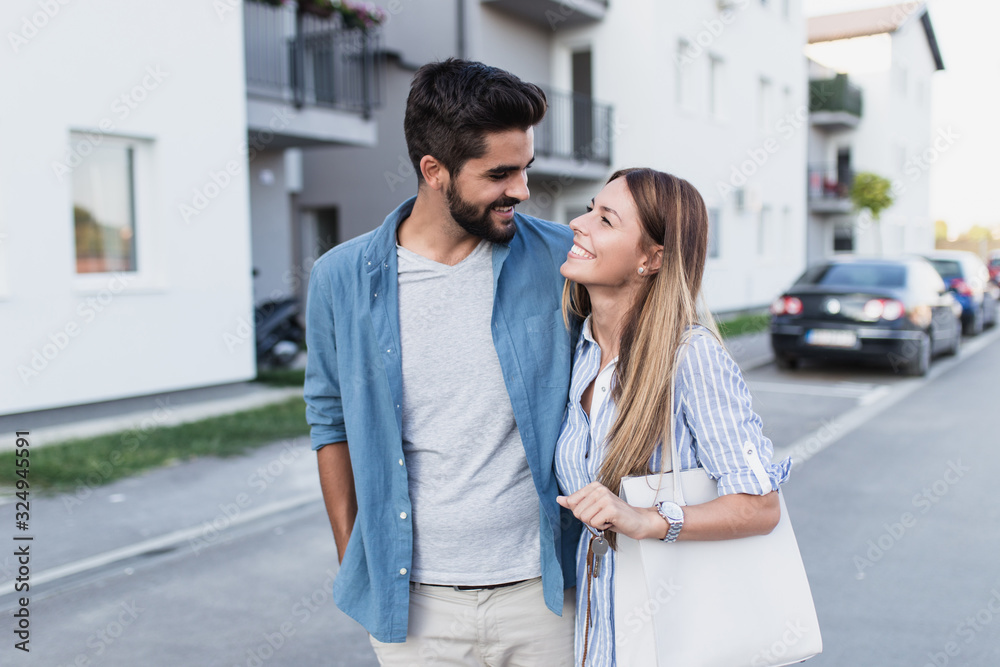 Beautiful happy young couple standing together outside in front of their new home. Beautiful happy young couple standing together outside in front of their new home.