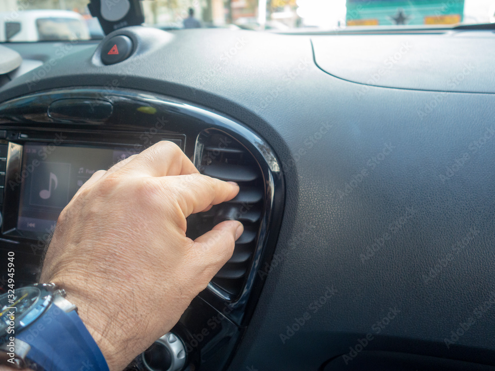 Man adjusting air conditioner in car