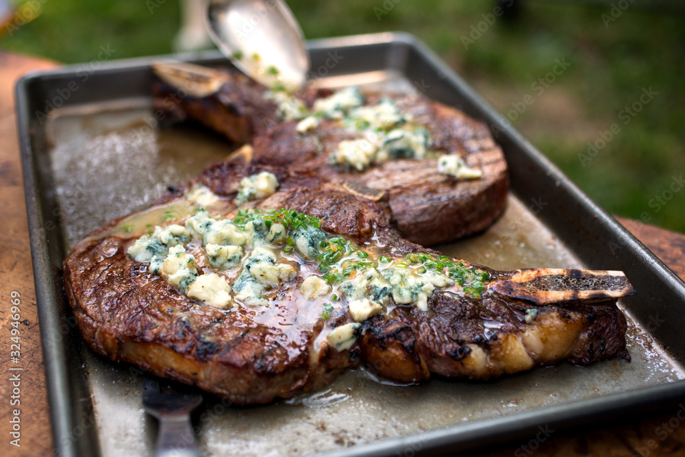 Grilled bone in rib eye with blue cheese and butter served in tray Grilled bone in rib eye with blue cheese and butter served in tray