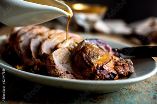 Selective focus of gravy pouring on roasted pork photo