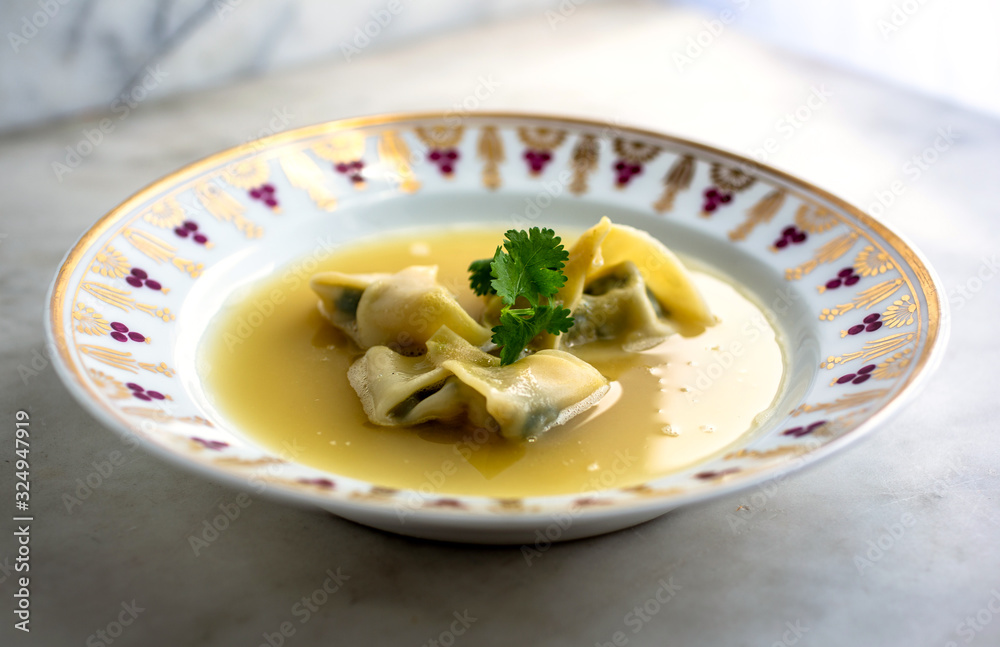 Spinach and tofu wontons with broth served on plate Spinach and tofu wontons with broth served on plate