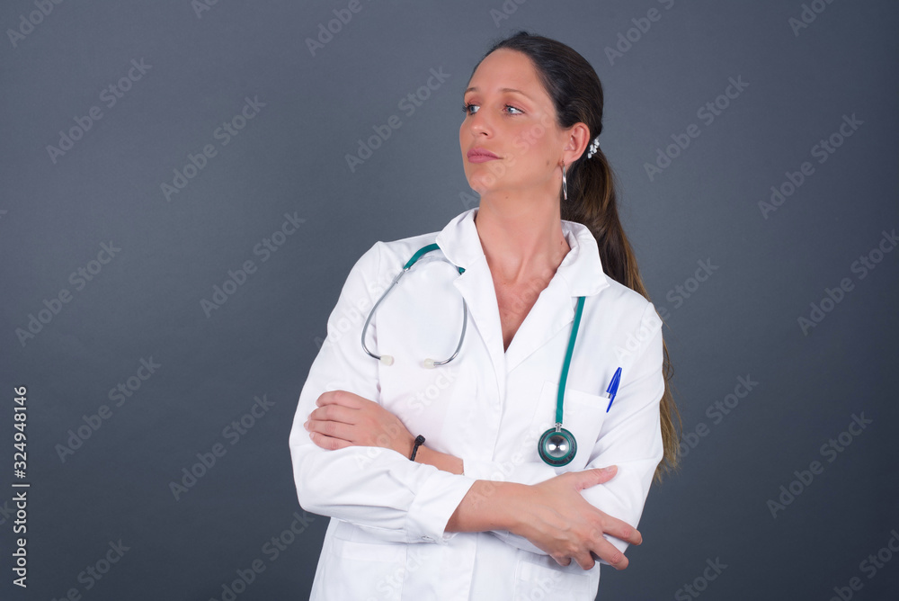 Image of upset pretty young caucasian lady standing indoors with arms crossed. Looking with disappointed expression aside after listening to bad news. Confident girl. Image of upset pretty young caucasian lady standing indoors with arms crossed. Looking with disappointed expression aside after listening to bad news. Confident girl.