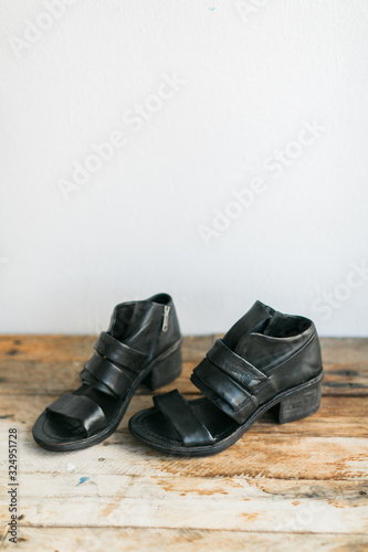 Black leather heeled sandals on wooden table